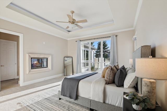 bedroom with ceiling fan, baseboards, a tray ceiling, ornamental molding, and carpet flooring