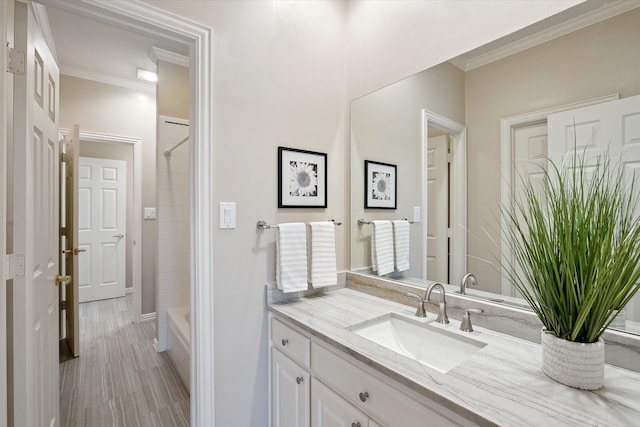 bathroom with wood finished floors, bathing tub / shower combination, ornamental molding, and vanity