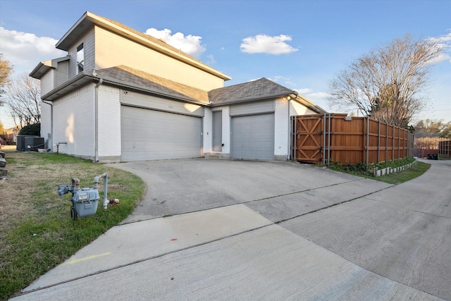 view of property exterior with brick siding, an attached garage, fence, driveway, and a gate