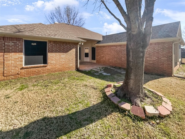 rear view of house featuring brick siding and a shingled roof