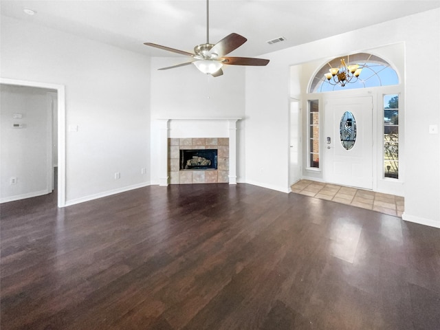 unfurnished living room featuring visible vents, ceiling fan with notable chandelier, wood finished floors, a fireplace, and baseboards