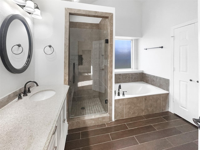 full bath with a bath, a stall shower, vanity, and wood finish floors