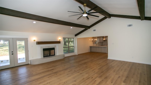 unfurnished living room with a wealth of natural light, visible vents, a brick fireplace, and wood finished floors