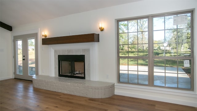 unfurnished living room with a fireplace with raised hearth and wood finished floors