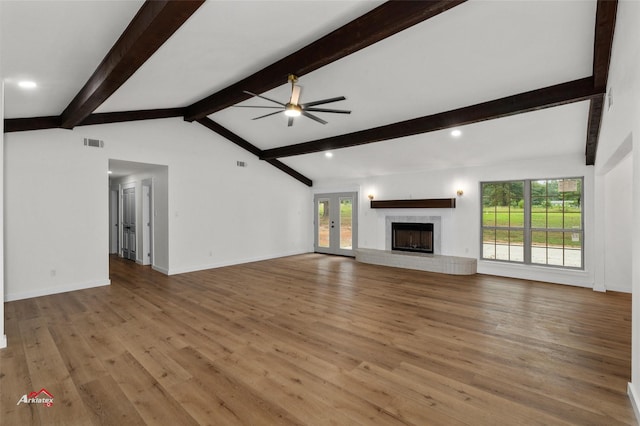 unfurnished living room featuring wood finished floors, visible vents, lofted ceiling with beams, a fireplace, and ceiling fan