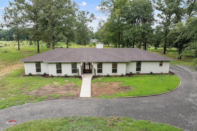 ranch-style house with brick siding, a chimney, a front yard, and roof with shingles