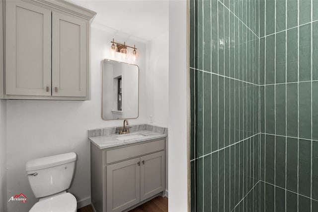 bathroom featuring toilet, vanity, and a tile shower