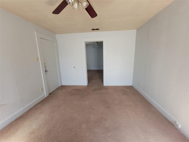 carpeted spare room with baseboards, visible vents, a textured wall, and ceiling fan