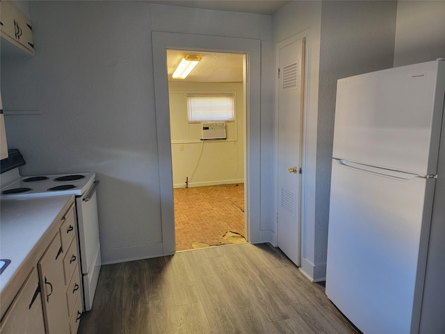 kitchen featuring baseboards, light countertops, wood finished floors, white cabinets, and white appliances