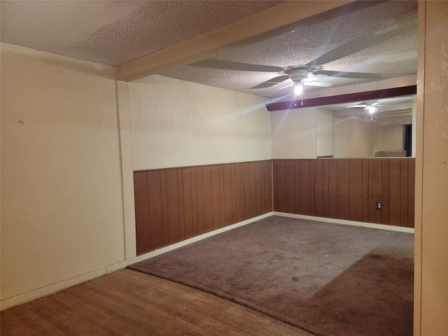 spare room featuring a wainscoted wall, a textured ceiling, wood finished floors, and wooden walls