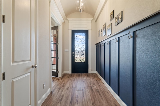 foyer entrance with wood finished floors, baseboards, and lofted ceiling