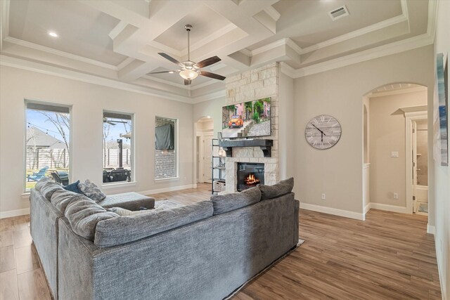 living area with arched walkways, visible vents, a ceiling fan, and crown molding