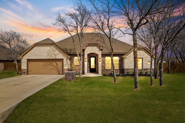 french country home with a garage, driveway, stone siding, and fence