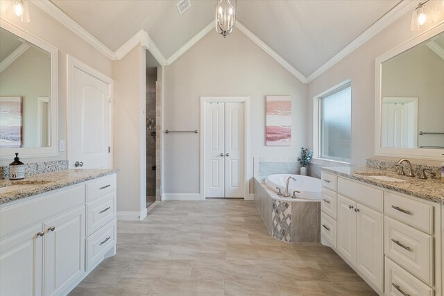 bathroom with two vanities, a bath, visible vents, lofted ceiling, and a sink