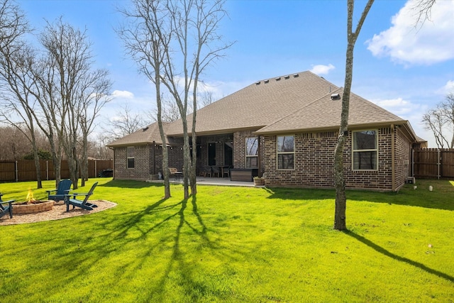 rear view of property with a fenced backyard, a lawn, a patio area, a fire pit, and brick siding