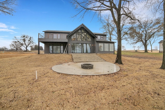 rear view of property with a wooden deck, an outdoor fire pit, and a patio