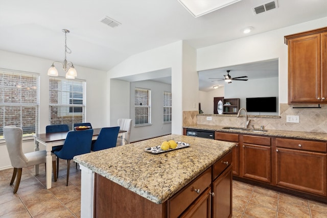 kitchen featuring visible vents, a sink, a center island, dishwasher, and vaulted ceiling