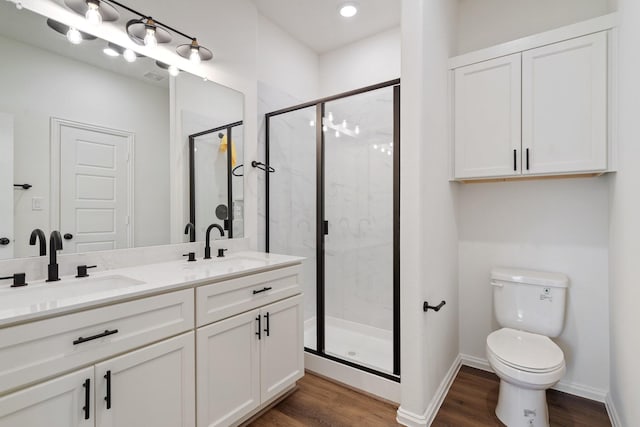 bathroom featuring a shower stall, toilet, wood finished floors, and a sink