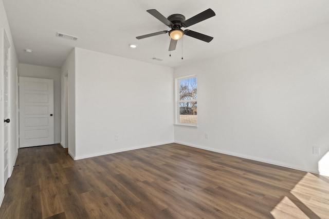 spare room with visible vents, baseboards, and dark wood-type flooring