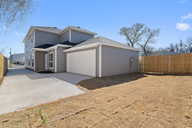 exterior space featuring concrete driveway, fence, and a garage