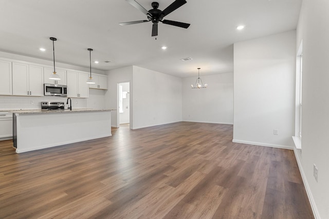 unfurnished living room with recessed lighting, wood finished floors, and ceiling fan with notable chandelier