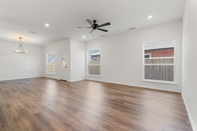 unfurnished living room featuring ceiling fan with notable chandelier, wood finished floors, and visible vents