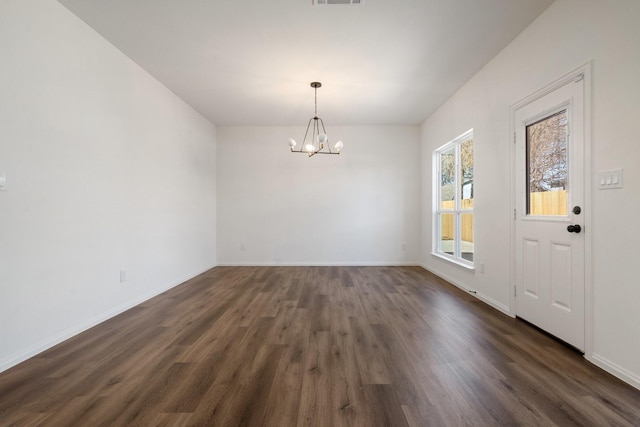 unfurnished dining area featuring dark wood finished floors, a chandelier, visible vents, and baseboards