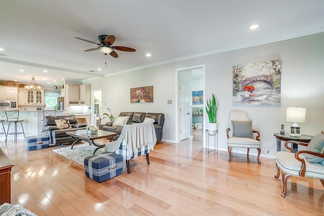 living area with ceiling fan, light wood-style flooring, baseboards, and ornamental molding