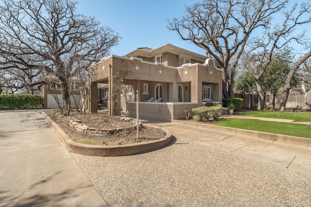 pueblo-style house featuring a front lawn and fence