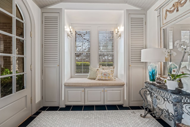 interior space with dark tile patterned flooring and vaulted ceiling