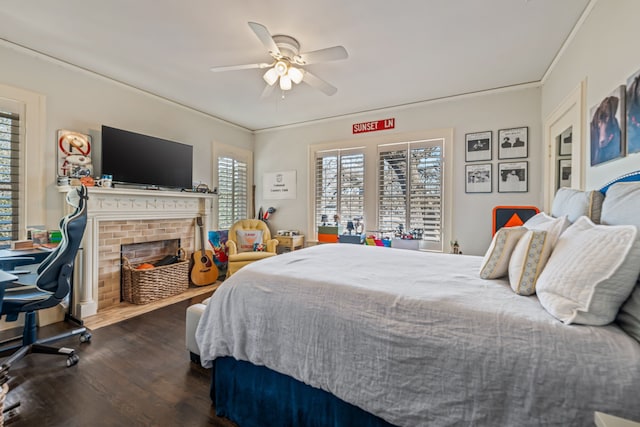 bedroom featuring a ceiling fan, multiple windows, a fireplace, and dark wood-style flooring