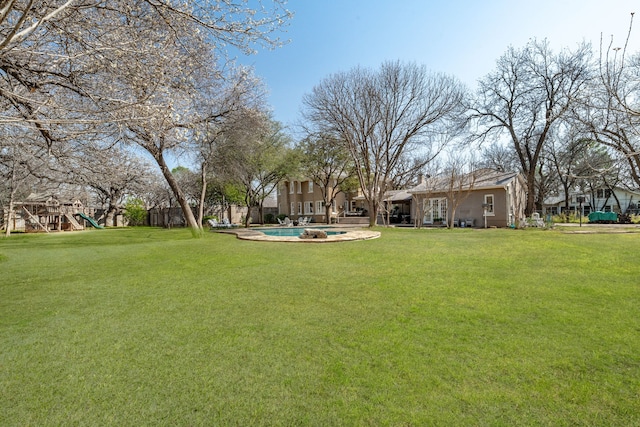 view of yard featuring a fenced in pool, playground community, and fence