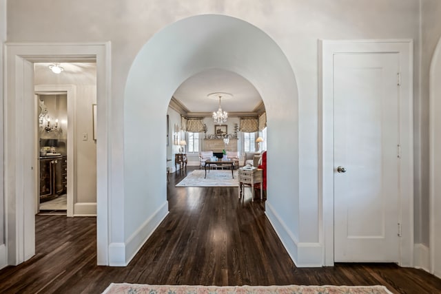 corridor with a chandelier, baseboards, wood finished floors, and crown molding