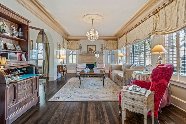 living room featuring baseboards, a chandelier, ornamental molding, wood finished floors, and arched walkways