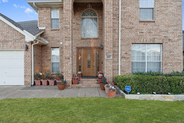 doorway to property with brick siding, a yard, and a garage