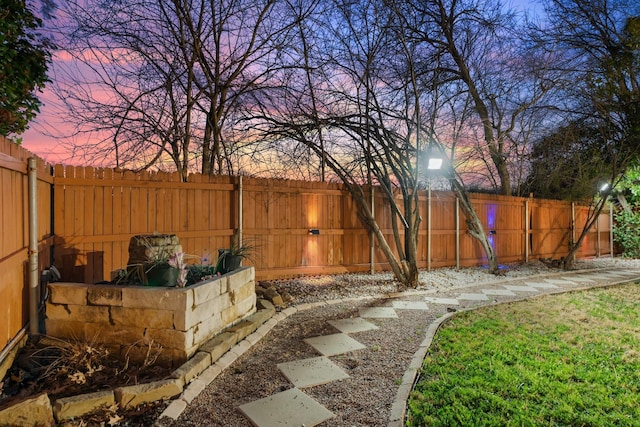 yard at dusk featuring a fenced backyard