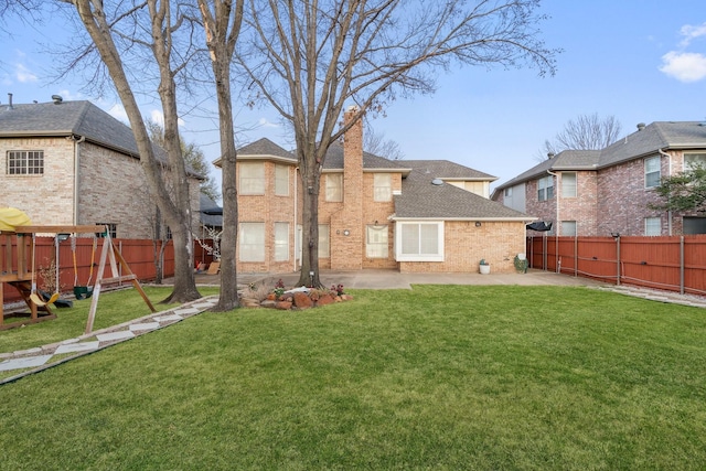 rear view of house with brick siding, a patio area, a playground, and a fenced backyard