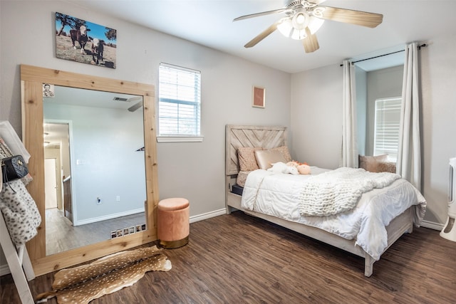 bedroom featuring ceiling fan, visible vents, baseboards, and wood finished floors