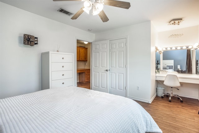 bedroom featuring visible vents, baseboards, built in desk, wood finished floors, and a closet