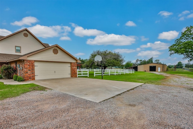 view of property exterior with brick siding, fence, a garage, a yard, and driveway