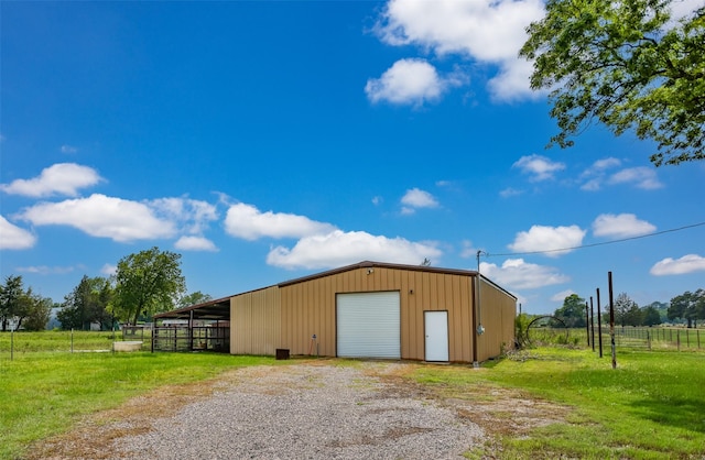 view of pole building with a yard, fence, and driveway