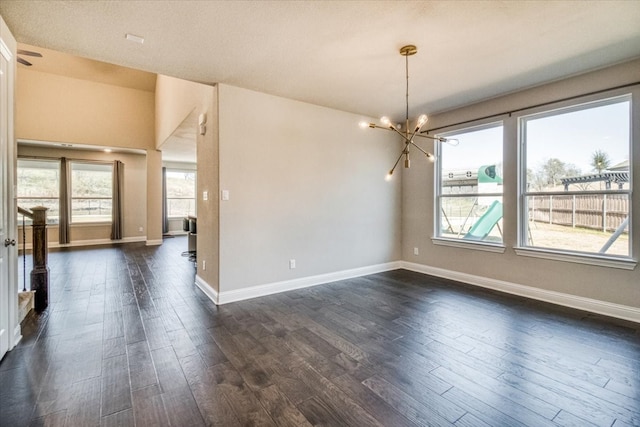 empty room featuring baseboards, dark wood-type flooring, and an inviting chandelier