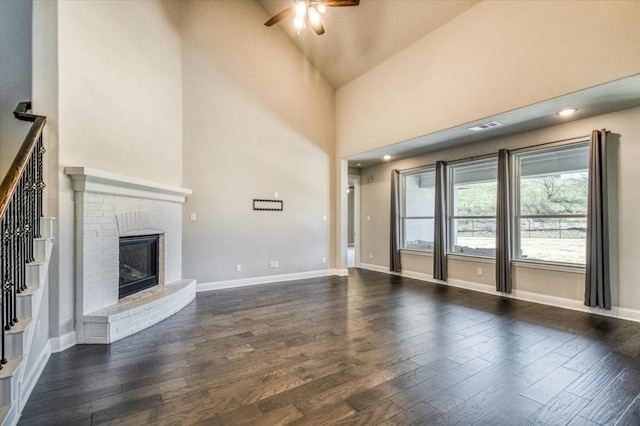 unfurnished living room featuring visible vents, a ceiling fan, dark wood-style floors, baseboards, and a brick fireplace