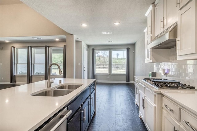 kitchen featuring visible vents, a sink, under cabinet range hood, stainless steel gas stovetop, and light countertops