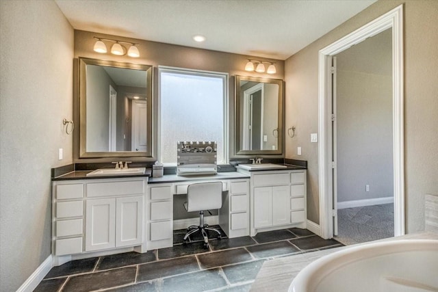 bathroom with double vanity, baseboards, and a sink