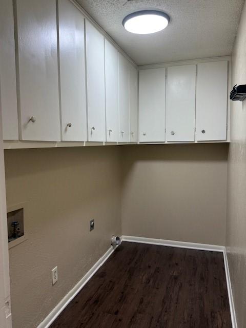 clothes washing area featuring hookup for a washing machine, hookup for an electric dryer, cabinet space, dark wood-style flooring, and a textured ceiling