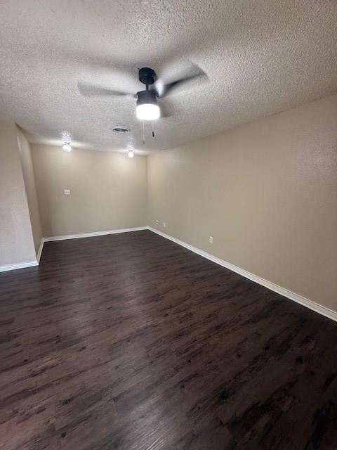 spare room with baseboards, a ceiling fan, dark wood-style flooring, and a textured ceiling