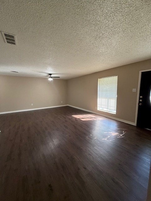 spare room featuring a ceiling fan, baseboards, visible vents, dark wood-type flooring, and a textured ceiling