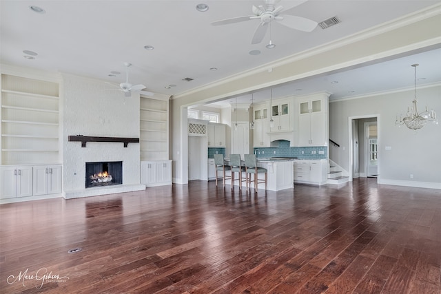 living area with crown molding, ceiling fan with notable chandelier, a fireplace, and visible vents