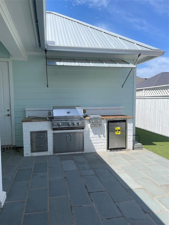 view of patio with grilling area, an outdoor kitchen, and fence